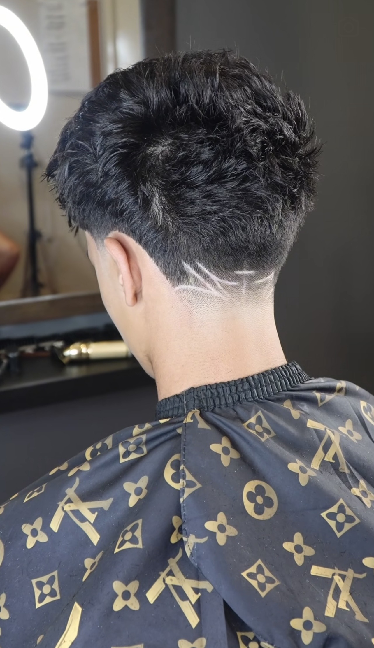 Back view of a clean fade under the Loui cape
